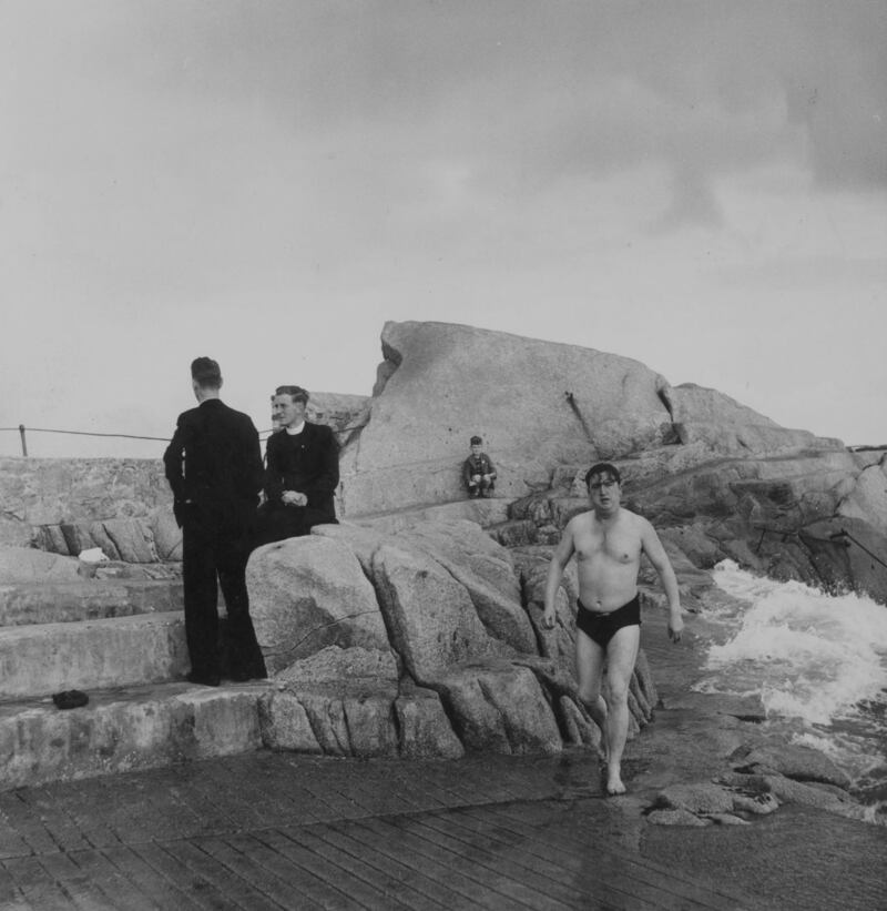 August 1952: Irish dramatist Brendan Behan strides along the sea rocks in his swimming costume. Photo by Daniel Farson/Picture Post/Getty Images