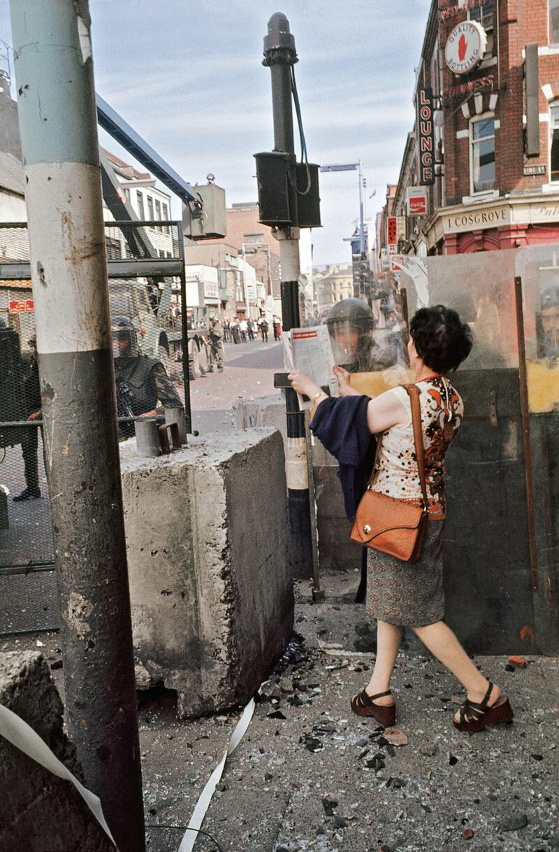 A woman stands at a British army barricade on King Street in Belfast around 1970.