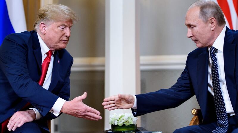 US president Donald Trump and Russian president Vladimir Putin reach to shake hands before a meeting in Helsinki on Monday. Photograph: Getty Images
