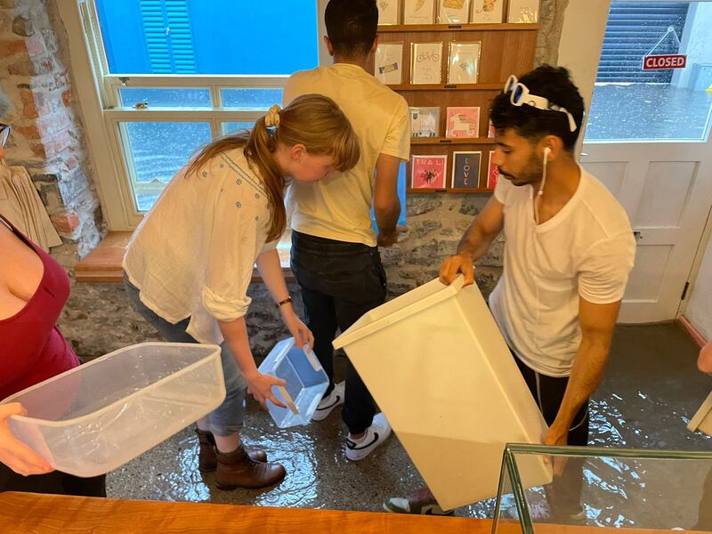 Customers at Maddens cafe in Tralee, Co Kerry help bail out water after downpour