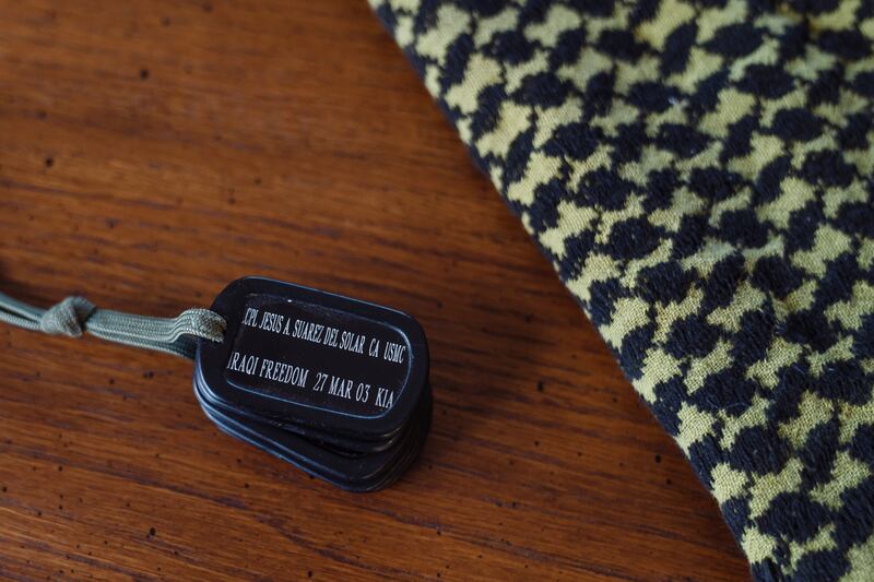 Two military keepsakes of retired marine Col Seth WB Folsom include dog tags made in honour of a soldier he led  who was killed by an American cluster munition -  and the scarf he was wearing on the day of the incident. Photograph: Ariana Drehseler/New York Times
                      