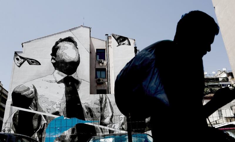 A man walks past a wall mural by the artist INO in Athens. Photo: Kostas Tsironis/Bloomberg