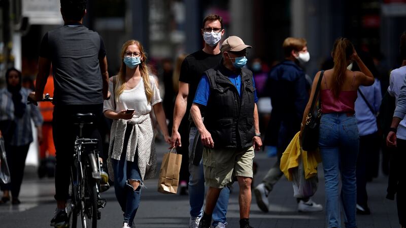 People wear protective face masks as they walk in the centre of Antwerp. To combat an outbreak of Covid-19 the city has imposed a curfew from 11.30pm to 6am. Photograph:  John Thys/AFP via Getty Images