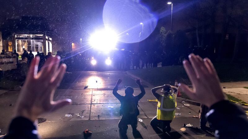 Protesters shout “Don’t shoot” while kneeling in front of a line of police officers at the Brooklyn Center police station in Minnesota during protests over the killing of Daunte Wright. Photograph: Kerem Yucel/AFP