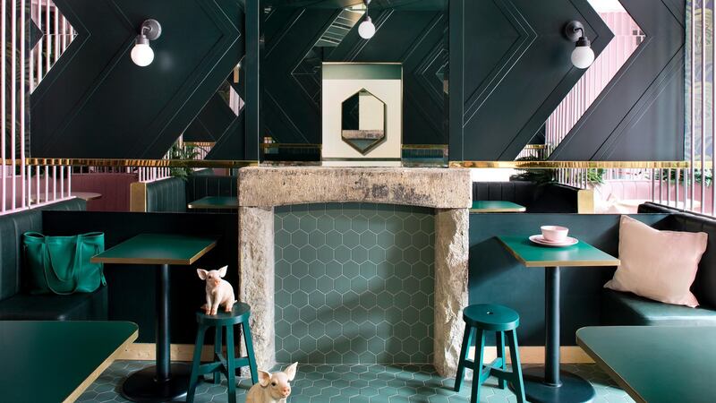 The pastel booths propped up by a backdrop of leaf-adorned wallpaper leading the eye to the hexagon teal tiles on the floor