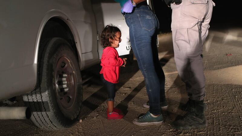 A two-year-old Honduran asylum seeker cries as her mother is searched and detained near the US-Mexico border on June 12th in McAllen, Texas. The asylum seekers had rafted across the Rio Grande from Mexico and were detained by US Border Patrol agents before being sent to a processing center for possible separation. Photograph:  John Moore/Getty Images