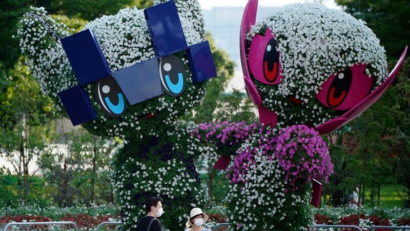 People wearing face masks stand before trees cut in the shape of the Tokyo 2020 Olympics mascots in Tokyo on Thursday. Photograph: Franck Robichon/EPA