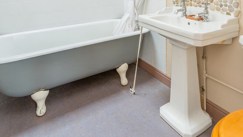 The bathroom at 2 Eden Road Lower in Glasthule has a free-standing claw-foot bath and a sink surround made of pebbles.