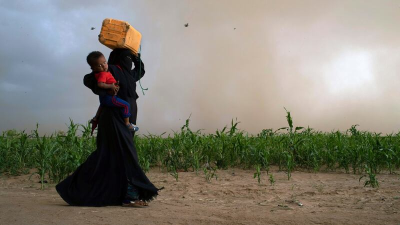 Fleeing an approaching storm, a woman heads towards her shelter at a camp for displaced people in Bani Hassan, Yemen. Photograph: Tyler Hicks/The New York Times