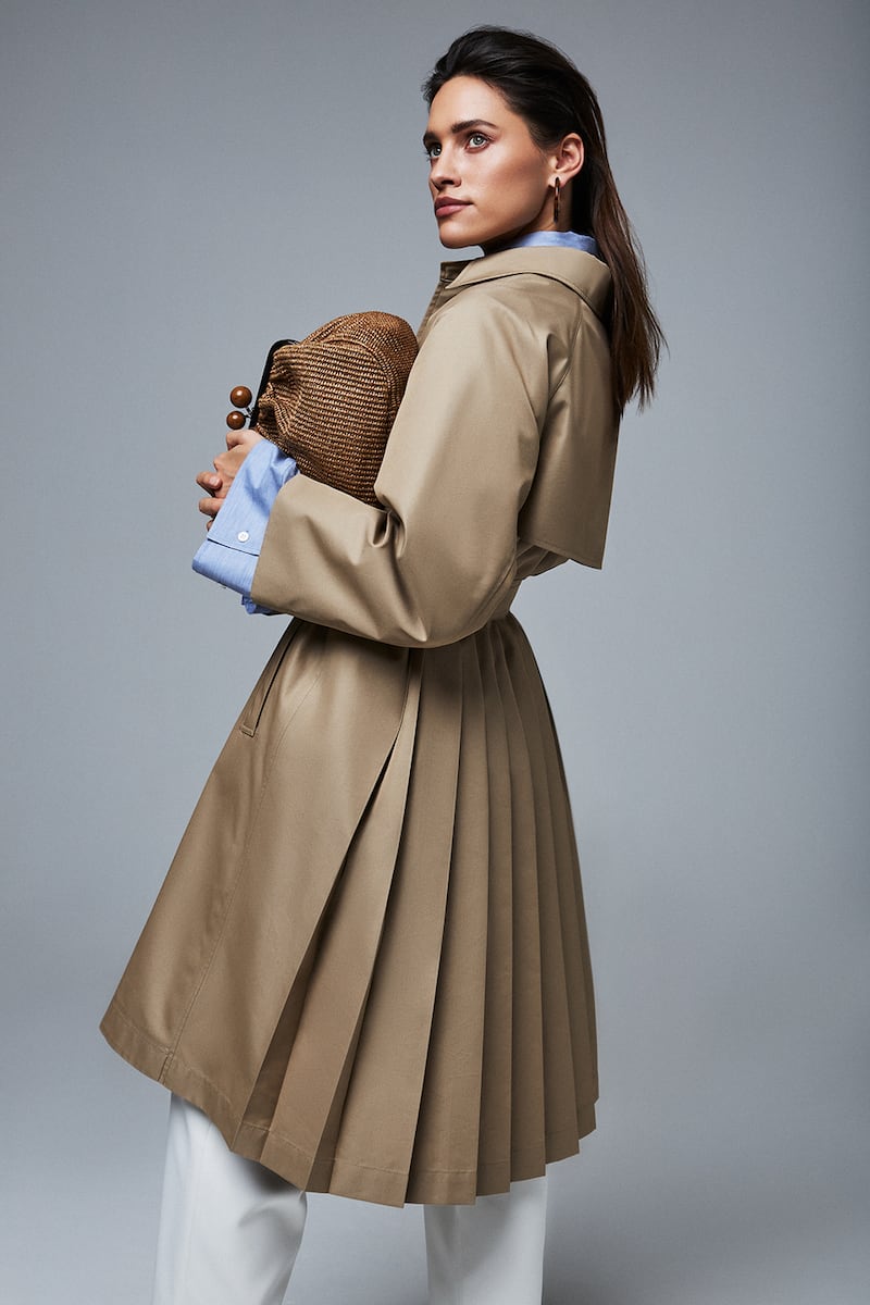 The trench; key investment piece. Pleated trench € 550 Weekend MaxMara, blue oversized shirt € 280 Acne, white trousers € 235 Solace London, tortoiseshell hoop earrings € 50 Kenneth Jay Lane, woven bag € 295 Weekend MaxMara
