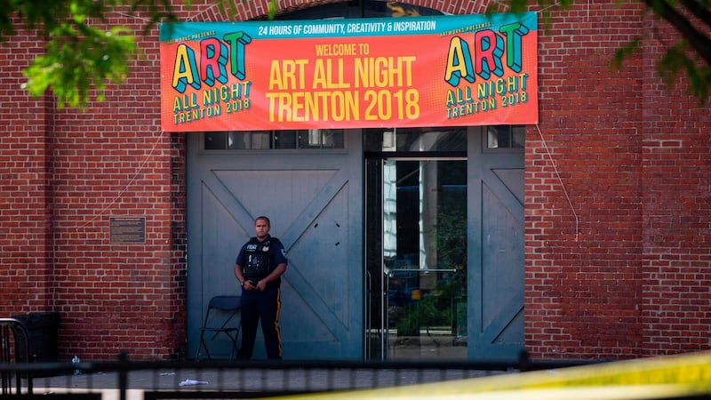 A police officer stands in front as other officers inspect the crime scene at the Roebling Market on  the morning after a shooting at an all-night art festival left  20 people injured and  one suspect dead in Trenton, New Jersey, US. Photograph: Dominick Reuter/AFP/Getty Images