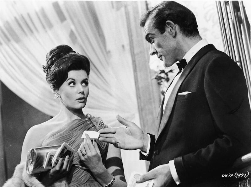 Scottish actor Sean Connery, as fictional secret agent James Bond, hands a business card to British actress Eunice Gayson in a scene from the film 'Dr. No,' directed by Terence Young, 1962. (Photo by MGM Studios/Courtesy of Getty Images) magazine