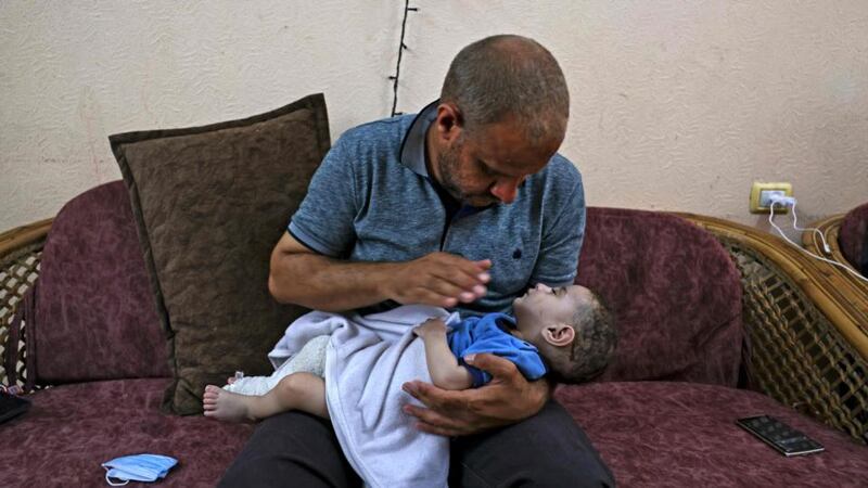 Muhammad al-Hadidi at his brother’s house holding his son Omar,  who was pulled alive from under the rubble after his mother and four brothers were killed in an Israeli air strike on May 15th. Photograph:  Mahmud Hams/AFP via Getty Images