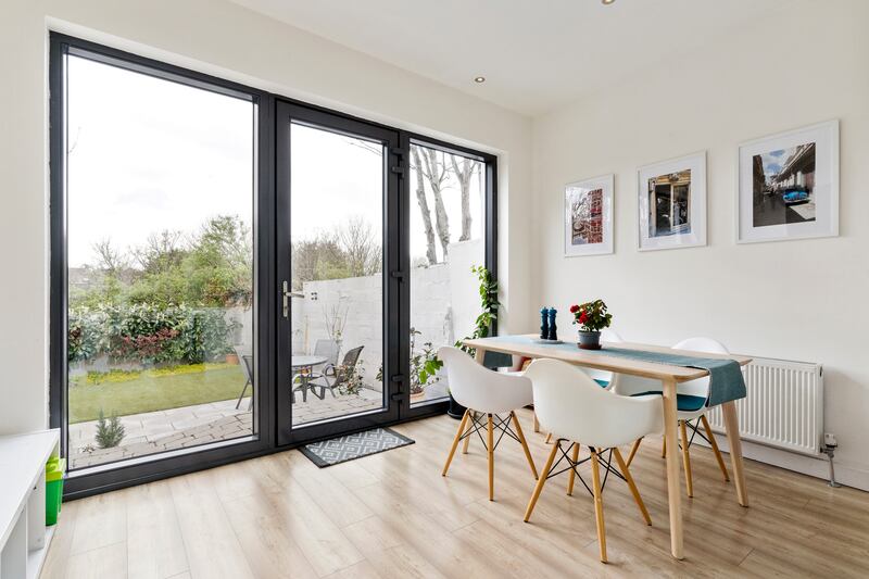 The dining area is a bright space with recessed lighting in the ceiling, benefiting from views incorporating the landscaped back garden and mature trees beyond