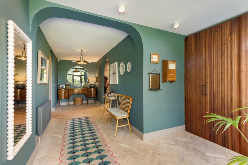 Double glass-panelled front doors open into the wide hallway, which has a series of arches and curved architraves