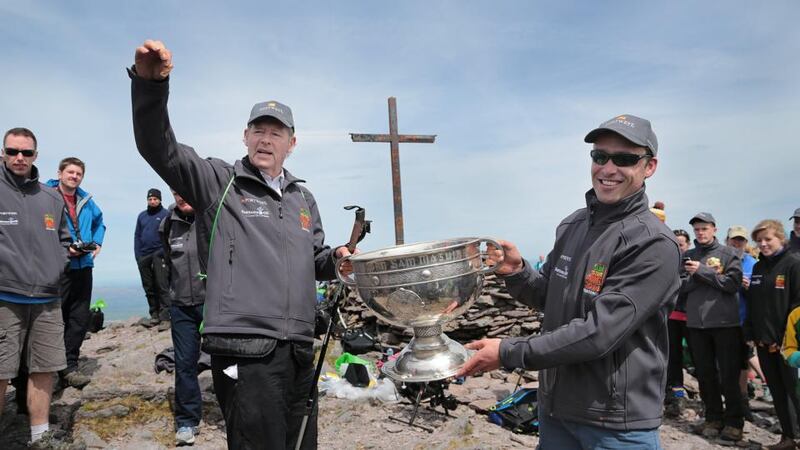 Legendary GAA commentator Mícheál Ó Muircheartaigh lifts the Sam Maguire Cup on the summit of Carrauntoohil, MacGillycuddy’s Reeks, Co Kerry, with programme director and former Galway star Alan Kerins during the ‘Sam to Summit’. Photo:  Valerie O’Sullivan/Sportsfile