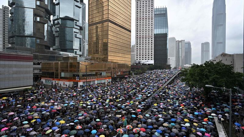 Protesters shelter under umbrellas during a downpour as they occupy roads near the government headquarters in Hong Kong. Photograph:  Anthony Wallace/AFP/Getty Images