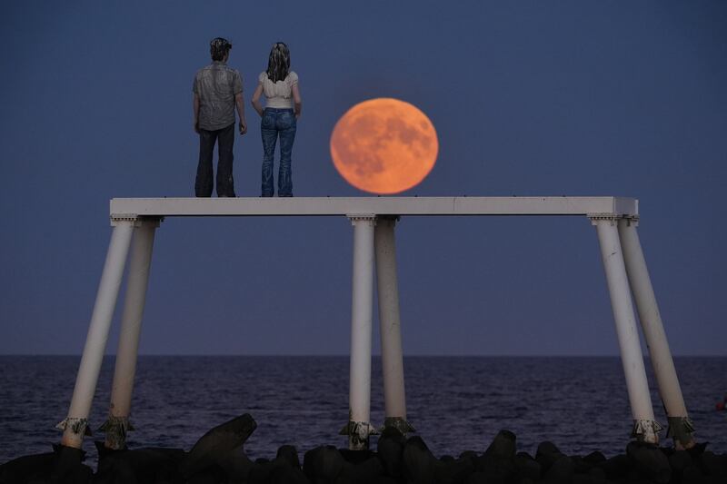 UK: Harvest moon rises over The Couple sculpture at Newbiggin-by-the-Sea in Northumberland. Photograph: Owen Humphreys/PA