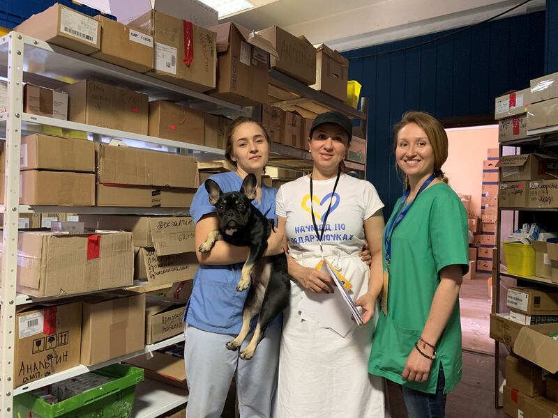 Maryna Tsonda (on far right) and two volunteers in the dispensary of the main humanitarian aid hub in Dnipro. Jessica the dog belonged to refugees and was adopted as a mascot by the centre. Photograph: Lara Marlowe
