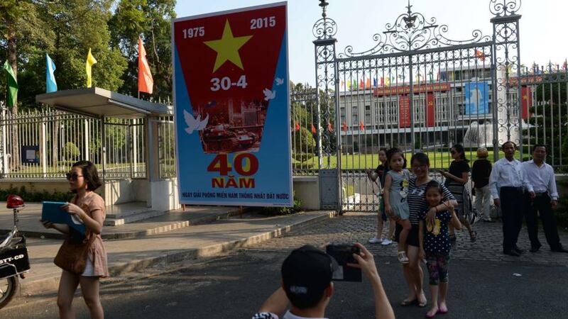 A family poses next to a poster marking the 40th anniversary of the fall of Saigon (now Ho Chi Minh City) placed at the front gates of the former presidential palace of the Southern Vietnamese regime in Ho Chi Minh Cit. Photograph:  Hoang Oang Dinh Nam/AFP/Getty Images
