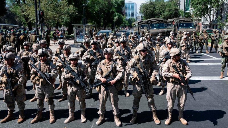Soldiers stand guard as police forces disperse protesters in Santiago, Chile on Monday. Photograph: Pedro Ugarte/ AFP/Getty