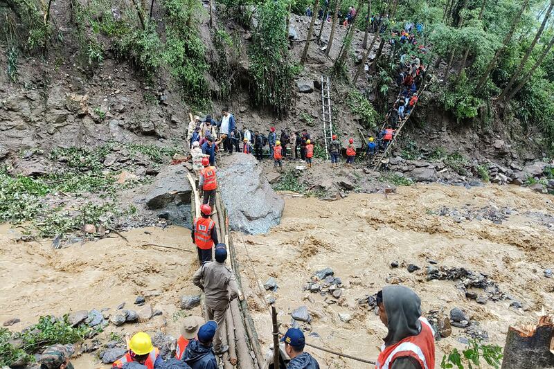 Tourists cross a river in Chungthang, in the Indian state of Sikkim, following landslides amid torrential rains. Photograph: INDIAN ARMY/AFP via Getty Images