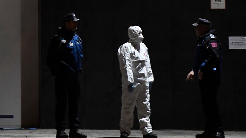 Policemen and a member of the Spanish Army’s Military Emergency Unit wearing a protective suit stand outside the Palacio de Hielo  shopping mall where an ice rink was turned into a temporary morgu. Photograph: Pierre-Philippe Marcou/AFP via Getty Images