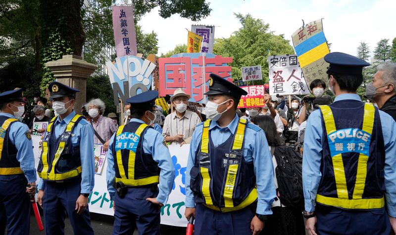 Police officers stand guard in front of protesters holding placards that say 'No!! State Funeral' during a rally against the state funeral of former prime minister Shinzo Abe in Tokyo, Japan. Photograph: Kimimasa Mayama/EPA