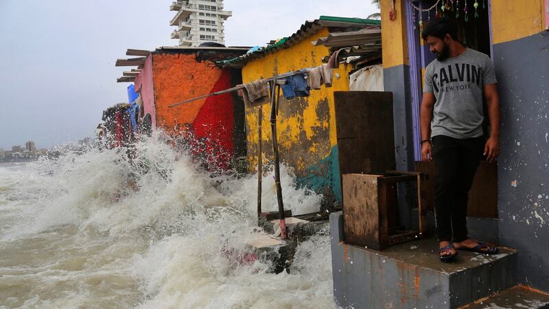 An Indian man stands near his house as waves caused by a high tide hit the huts on the shore of the Arabian Sea in Mumbai on Wednesday. Photograph: Rafiq Maqbool/AP