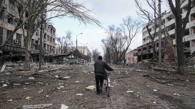 A man walks with a bicycle in a street damaged by shelling in Mariupol, Ukraine. Photograph: Evgeniy Maloletka/AP