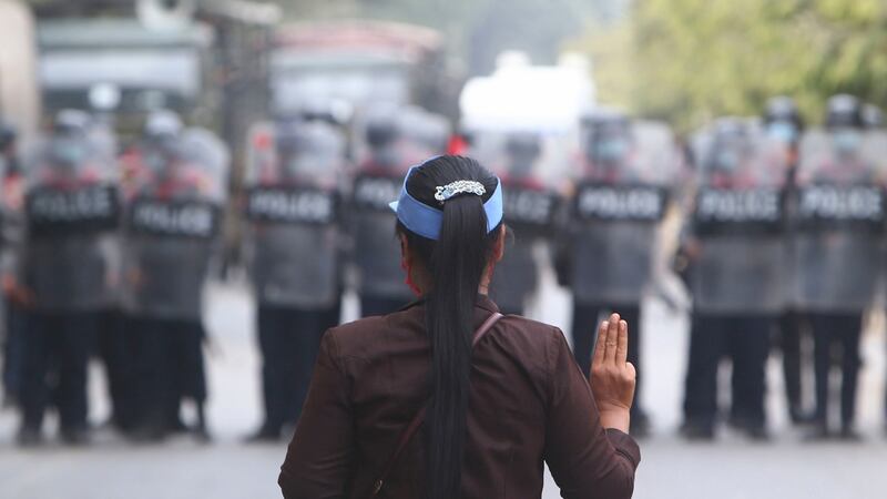 A female protester flashes the three-fingered salute in front of police in Mandalay on Saturday. Photograph: AP