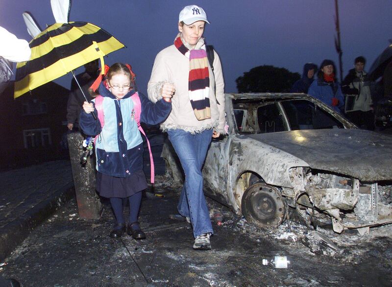A pupil from Holy Cross Primary School makes her way up the Ardoyne Road with an adult January 11th, 2002, after two nights of lrioting in the area.Photograph: Haydn West/PA
