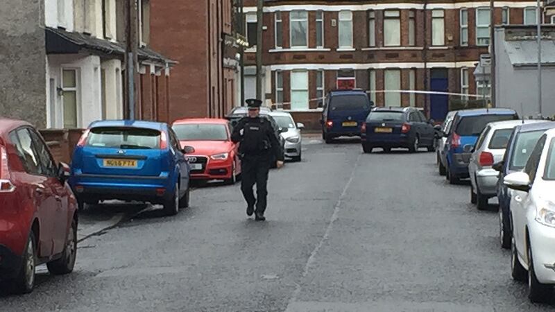 A police officer at the scene where a van (centre, top) under which a device exploded in east Belfast, leaving a man injured. Photograph: Lesley-Anne McKeown/PA Wire.