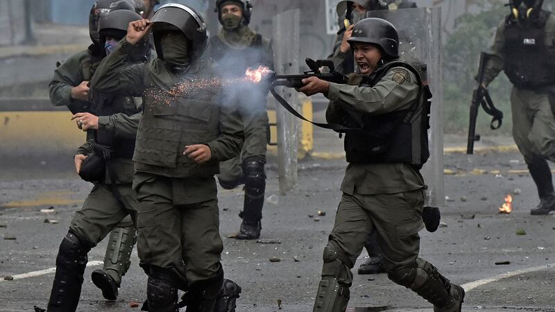 A member of the national guard fires his shotgun at opposition demonstrators during clashes in Caracas on Friday. Photograph: Carlos Becerr