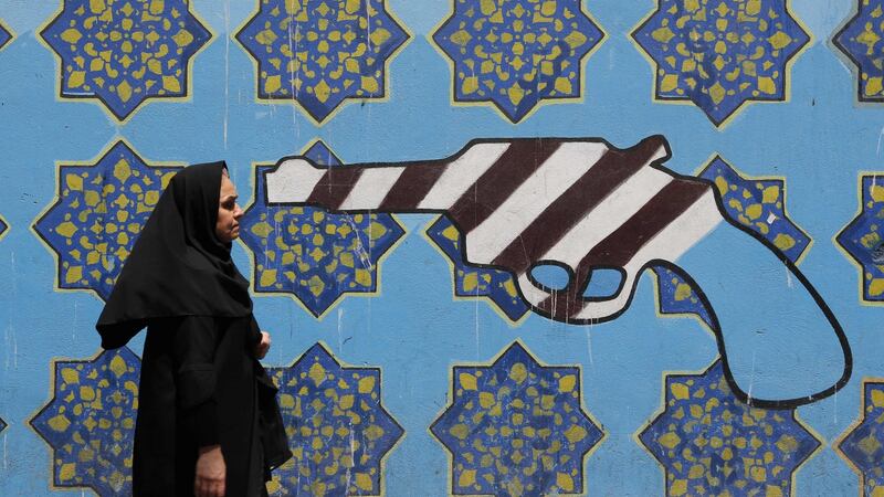 An Iranian woman walks past a mural depicting a gun painted on the wall of the former US embassy in the capital Tehran. Photograph: Getty Images