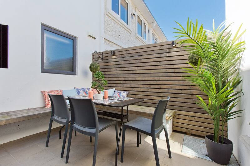 The garden has a paved dining terrace that steps up to a green area laid in artificial grass.