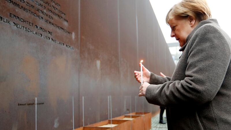 German Chancellor Angela Merkel lights a candle at the memorial of the divided city and the victims of communist tyranny during a ceremony marking the 30th anniversary of the fall of the Berlin Wall. Photograph: Fabrizio Bensch/Reuters.