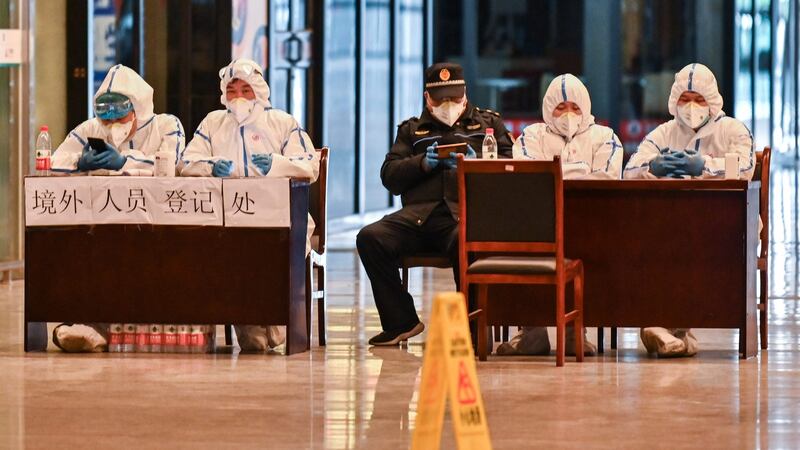 Workers in protective gear wait for passengers arriving at the railway station in Wuhan, China’s central Hubei province on Saturday after travel restrictions into the city were eased. Photograph: Hector Retamal/AFP via Getty Images