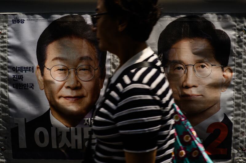 A woman in Seoul walks past a banner showing Lee Jae-myung, the presidential candidate for the Democratic Party, and Kim Moon Soo, the People Power Party's contender. Photograph: Anthony Wallace/Getty