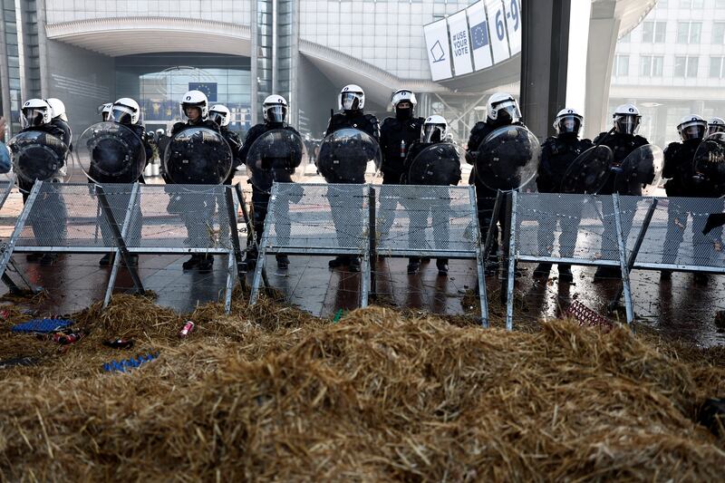 Riot police stand outside the European Parliament building in Brussels, as protesting farmers clogged roads around an EU summit with about 1,300 tractors. Photograph: SAMEER AL-DOUMY/AFP via Getty Images