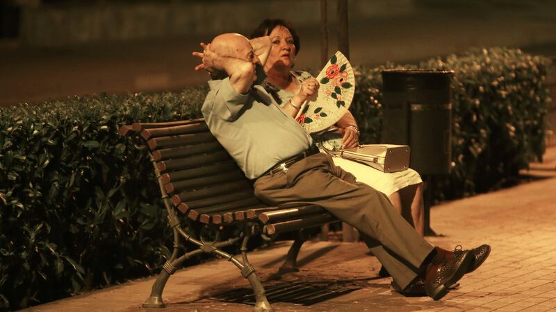 A woman fans herself as she and a man rest on a bench in Ronda, southern Spain. Photograph: Reuters