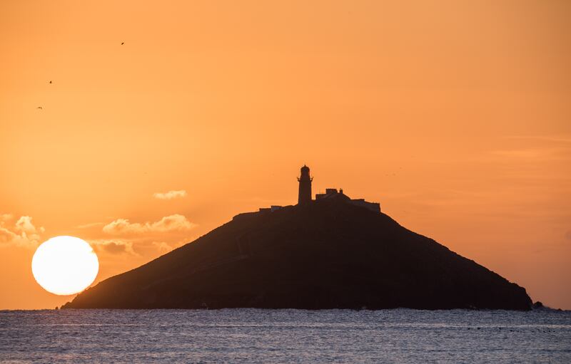 The sun begins to rise behind the island in Ballycoton Bay, Co Cork.  Photograph: David Creedon