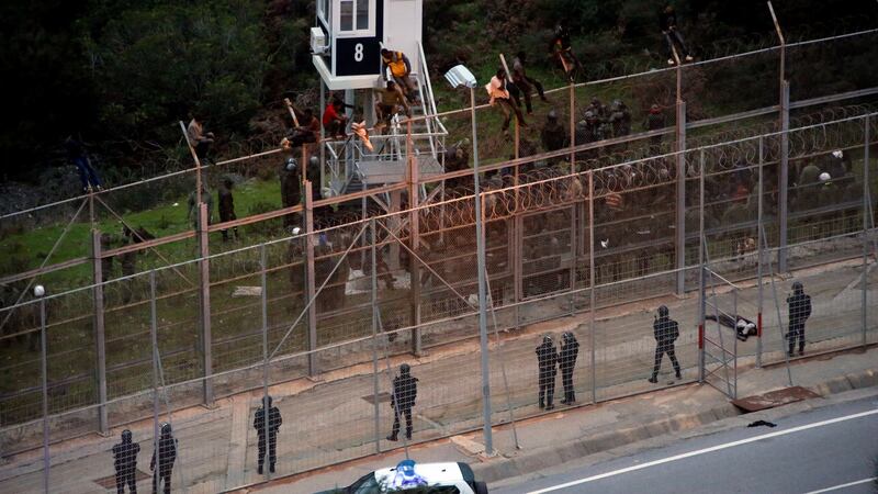 African migrants sit on top of a border fence during an attempt to cross into Spanish territories, between Morocco and Spain’s north African enclave of Ceuta. Photograph: M Martin/Reuters