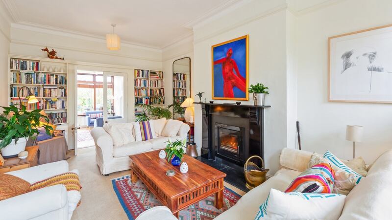 Cosy sitting room, with squishy, linen-covered seating set around a black painted fire surround, with an inset Heat Design stove