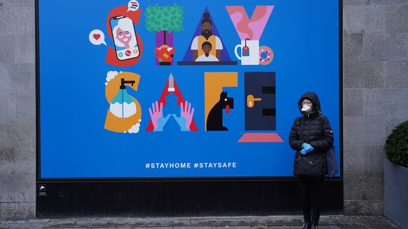 A woman wearing a protective mask stands next to a billboard hanging on the temporarily shuttered KaDeWe department store in Berlin, Germany. Photograph: Sean Gallup/Getty