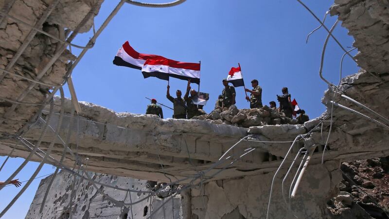 Syrian government forces’ soldiers wave their national flags after taking back the city of Quneitra. Photograph: AFP