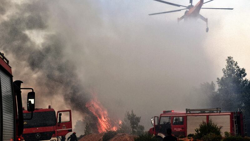 A firefighting helicopter and firemen work to extinguish a wildfire  in Verori, near Loutraki city, southern Greece, on Tuesday. Photograph: Vassilis Psomas/EPA
