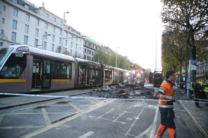 Workers clear debris from a burned-out Luas tram on O'Connell Street in Dublin in November 2023 after rioting and looting. Photograph: Stephen Collins/Collins 
