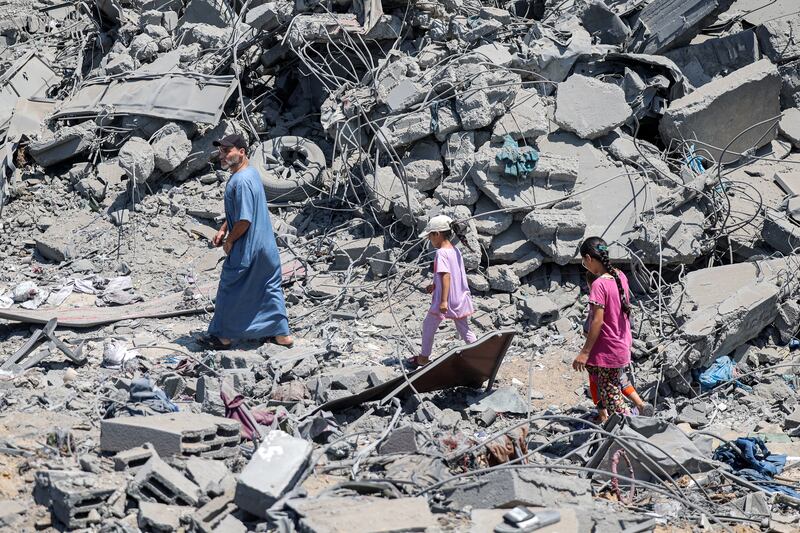 A man and children walk through rubble at the site of a building hit by Israeli bombardment in the Sabra neighbourhood in Gaza City. Photograph: Omar Al-Qattaa/AFP via Getty Images