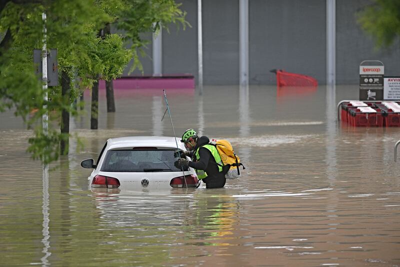 An alpine rescuer looks in a car for missing persons near a supermarket in a flooded area in Cesena on Wednesday. Photograph: Alessandro Serrano/AFP via Getty Images